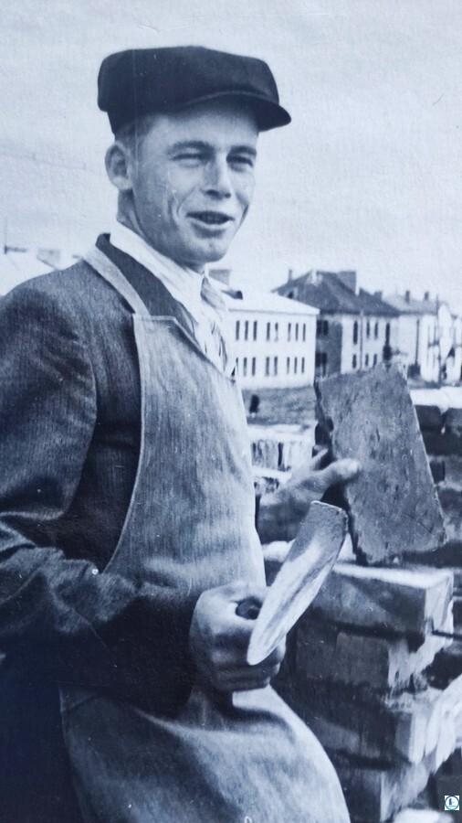 Передовой каменщик комплексной бригады 2-го СУТ №12 Н. Г. Королевич ежедневно выполняет производственные нормы на 180-200%. На снимке парень в пиджаке и при галстуке — видимо, по случаю предстоящего награждения после смены, Молодечно, 27 октября 1960 года